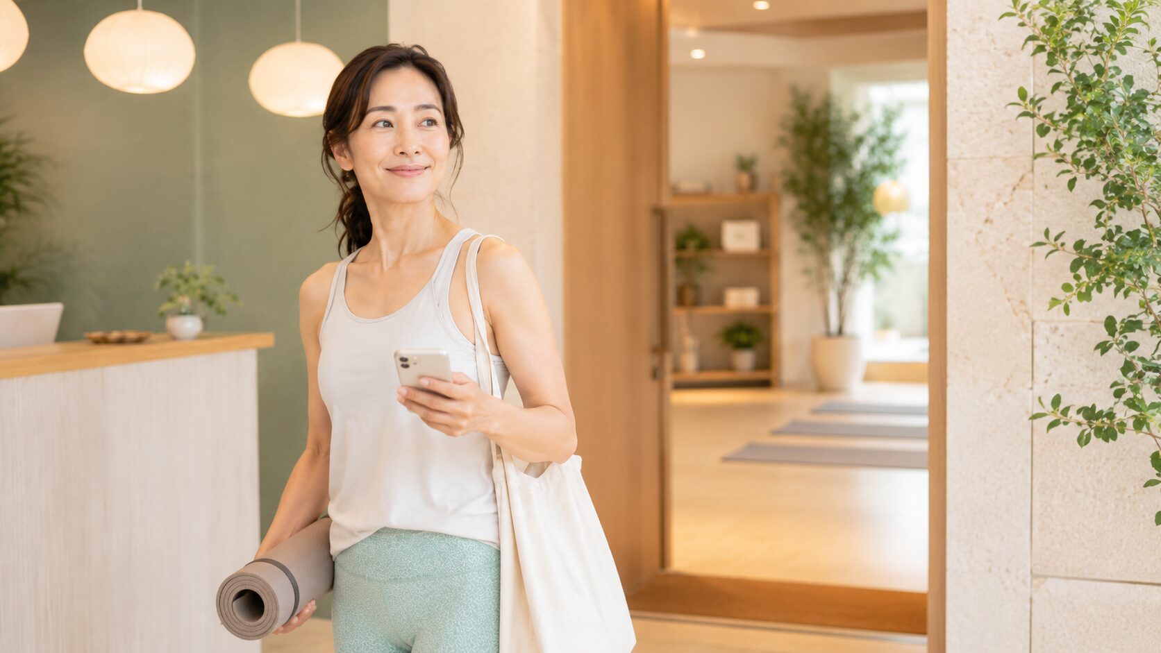 ヨガマットとバッグを持ってスタジオに到着した女性